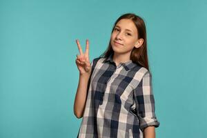 lindo Adolescência menina dentro uma casual xadrez camisa é posando contra uma azul estúdio fundo. foto