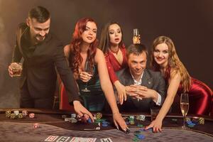 grupo do uma jovem rico amigos estão jogando pôquer às uma casino. foto