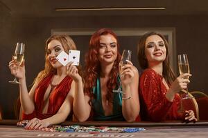 três lindo jovem mulheres estão jogando pôquer às uma casino. foto