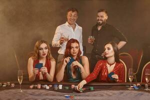 grupo do uma jovem rico amigos estão jogando pôquer às uma casino. foto