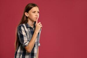 lindo Adolescência menina dentro uma casual xadrez camisa é posando contra uma Rosa estúdio fundo. foto