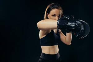 Atlético mulher dentro boxe luvas é praticando karatê dentro estúdio. foto