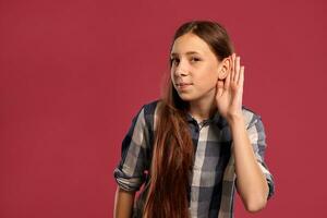 lindo Adolescência menina dentro uma casual xadrez camisa é posando contra uma Rosa estúdio fundo. foto