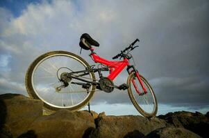 uma vermelho montanha bicicleta é sentado em topo do uma rochoso penhasco foto