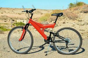 uma vermelho montanha bicicleta estacionado em a lado do a estrada foto