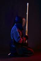 fechar acima tomada, kendo lutador vestindo dentro a armaduras, tradicional quimono, capacete praticando marcial arte com Shinai bambu espada, Preto fundo. foto