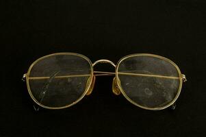 uma par do óculos com ouro aros em uma Preto fundo foto