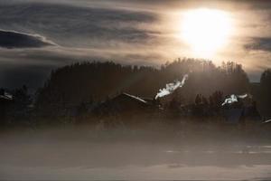 fumaça das chaminés de uma aldeia na montanha no frio da entrada ao pôr do sol foto