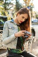 feliz hipster menina fazer foto com retro Câmera em cidade rua