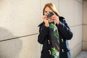 feliz hipster menina fazer foto com retro Câmera em cidade rua