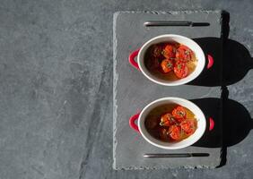 cozido cereja tomates dentro repartido panelas debaixo luz solar em a mesa, plana deitar, Difícil luz, ingrediente para caprese apetitoso foto