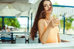 sexy jovem mulher com grandes cabelo bebendo coquetel às a de praia bar. foto