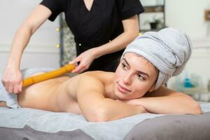 jovem mulher obtendo uma costas massagem dentro uma spa salão. beleza tratamento conceito. foto