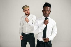 amigos. dois rapazes dentro branco camisas e Sombrio calça posando dentro a estúdio em uma branco fundo foto