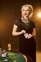 uma mulher dentro uma Preto vestir com cartões dentro dela mãos é em pé perto a pôquer mesa foto