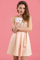 jovem lindo mulher segurando a ganhando combinação do pôquer cartões em Rosa fundo. dois ases foto