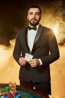 uma jovem homem dentro uma o negócio terno em pé perto pôquer mesa. homem jogos de azar. foto
