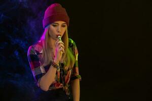 Cigarro eletrônico garota. jovem hipster mulher vape e-cig em Preto fundo. hip-hop estilo. estúdio tiro foto