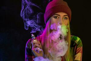 Cigarro eletrônico garota. jovem hipster mulher vape e-cig em estúdio em Preto fundo. hip-hop estilo. fechar acima. foto