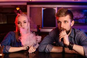 uma homem e mulher fumar eletrônico cigarro dentro uma vape bar. foto