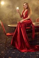 jovem lindo mulher é posando contra uma pôquer mesa dentro luxo casino. foto