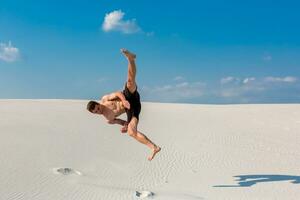 retrato do jovem Parkour homem fazendo giro ou cambalhota em a areia. foto