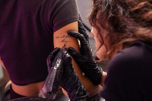 talentoso artista construindo personalizado letras tatuagem em fêmea braço foto