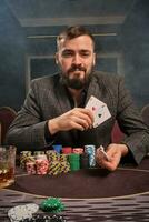 bonito barbudo homem é jogando pôquer sentado às a mesa dentro casino. foto