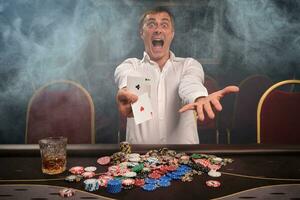 bonito emocional homem é jogando pôquer sentado às a mesa dentro casino. foto