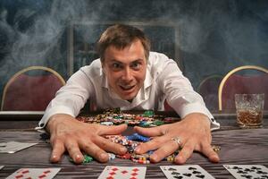 bonito emocional homem é jogando pôquer sentado às a mesa dentro casino. foto