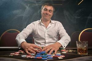 bonito emocional homem é jogando pôquer sentado às a mesa dentro casino. foto