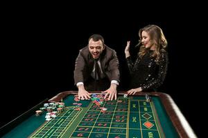 homem com mulher jogando roleta às a casino. vício para a foto