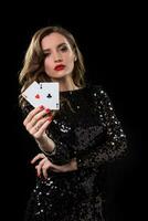 jovem mulher segurando jogando cartões contra uma Preto fundo foto