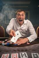 bonito emocional homem é jogando pôquer sentado às a mesa dentro casino. foto