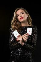 jovem mulher segurando jogando cartões contra uma Preto fundo foto