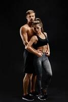 esporte, fitness, exercite-se conceito. em forma casal, Forte muscular homem e fino mulher posando em uma Preto fundo foto