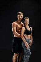 esporte, fitness, exercite-se conceito. em forma casal, Forte muscular homem e fino mulher posando em uma Preto fundo foto