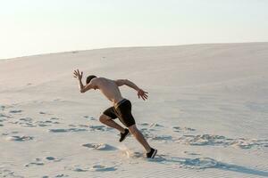 em forma homem corrida velozes em a areia. poderoso corredor Treinamento ao ar livre em verão. foto