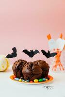 dia das Bruxas chocolate bolos com doces e papel morcegos em Rosa fundo foto