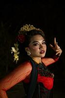 fechar acima do a indonésio mulher dentro uma balinesa dançarino traje posando muito belas às noite foto