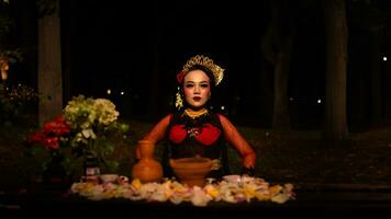 uma fêmea dançarino quem parece lindo dentro uma vermelho traje executa uma ritual este irradia a aura do beleza e pureza foto