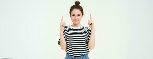 estilo de vida e propaganda conceito. jovem sorridente mulher, moderno garota, apontando dedo às promoção, mostrando bandeira, Lugar, colocar com texto, isolado em branco fundo foto