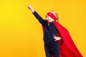 engraçado pequeno poder Super heroi criança menina dentro uma vermelho capa de chuva e uma mascarar. Super heroi conceito. foto