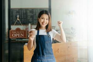 jovem fêmea suspensão uma bem-vinda placa dentro frente do uma café fazer compras. lindo garçonete ou anfitriã segurando uma tábua preparando dentro uma restaurante. foto