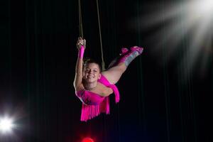 circo artista acrobata desempenho. a menina executa acrobático elementos dentro a ar. circo ginasta em a etapa foto