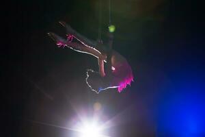 circo artista acrobata desempenho. a menina executa acrobático elementos dentro a ar. circo ginasta em a etapa foto