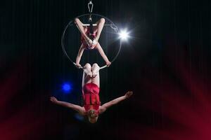 circo atriz acrobata desempenho. dois meninas executar acrobático elementos dentro a ar anel. foto