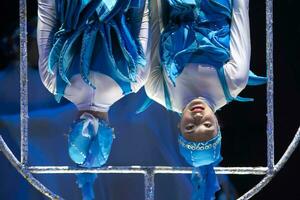 dois acrobata meninas mostrar uma circo número em uma Sombrio fundo. acrobático desempenho. foto