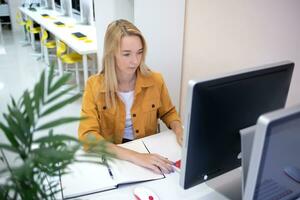 jovem mulher senta às uma computador dentro a escritório. controlo remoto trabalhos conceito foto