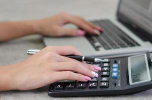 mão de mulher segurando uma caneta e uma calculadora. finanças, impostos e negócios de investimento. foto